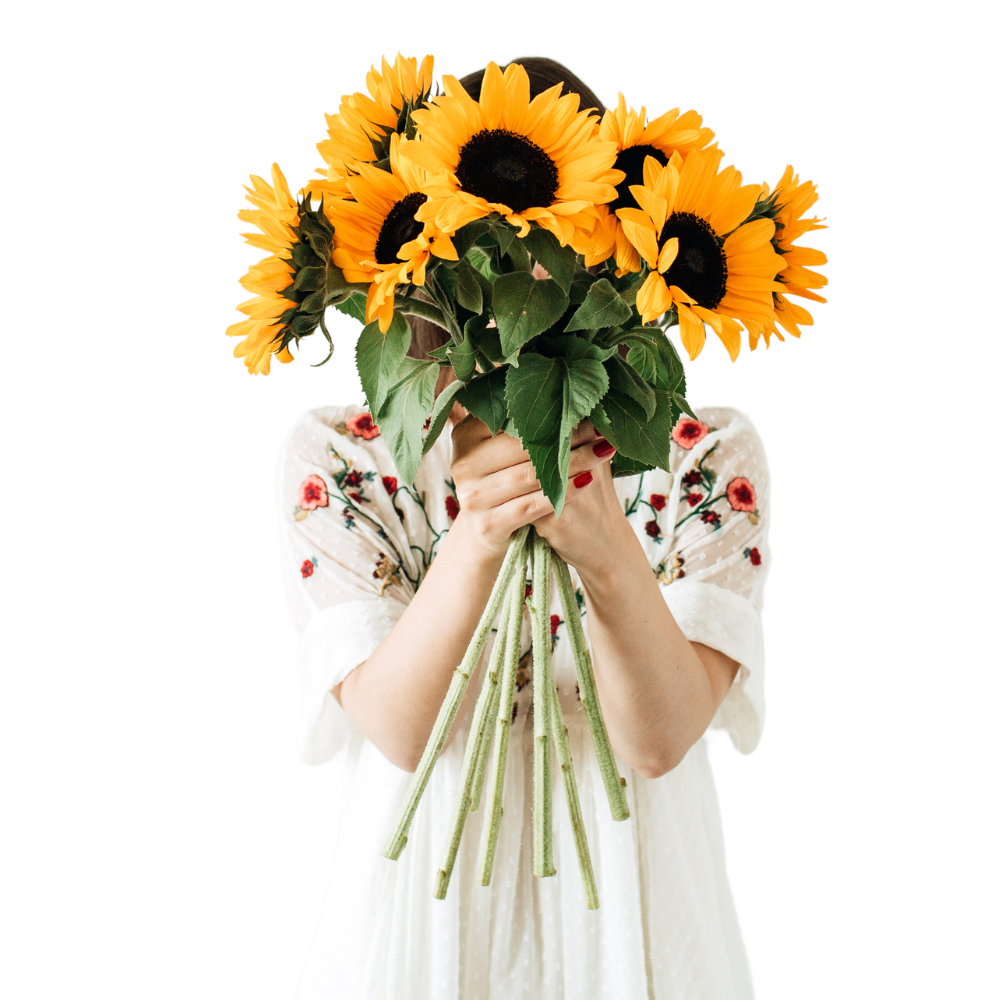 someone holding sunflowers in front of their face